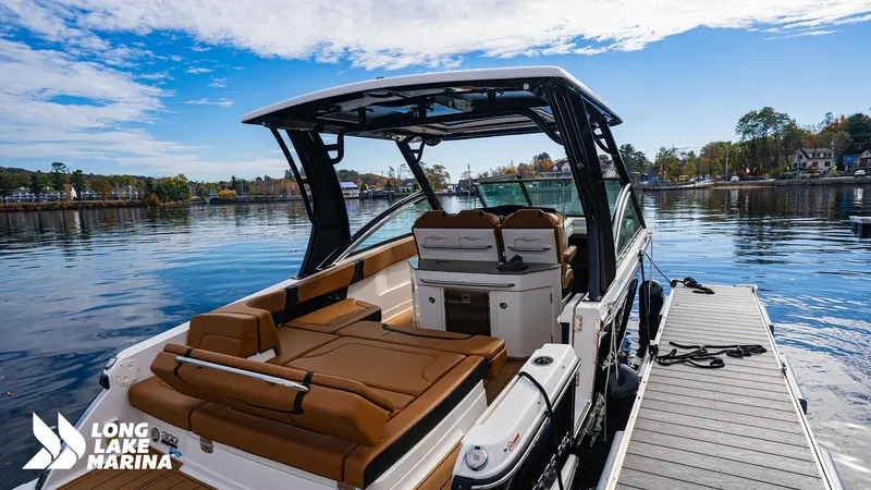 Slide: The Image of 2024 Chaparral 300 OSX boat docked at Long Lake Marina under a clear blue sky. - 2
