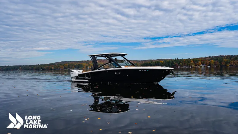 Slide: The Image of 2024 Chaparral 300 OSX boat on a calm lake under a cloudy sky. - 4