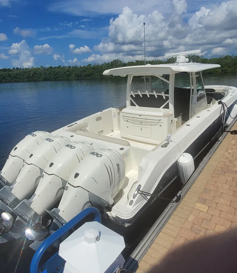 The Image of 2020 Boston Whaler 380 Outrage docked by a serene lake under a blue sky. - 0