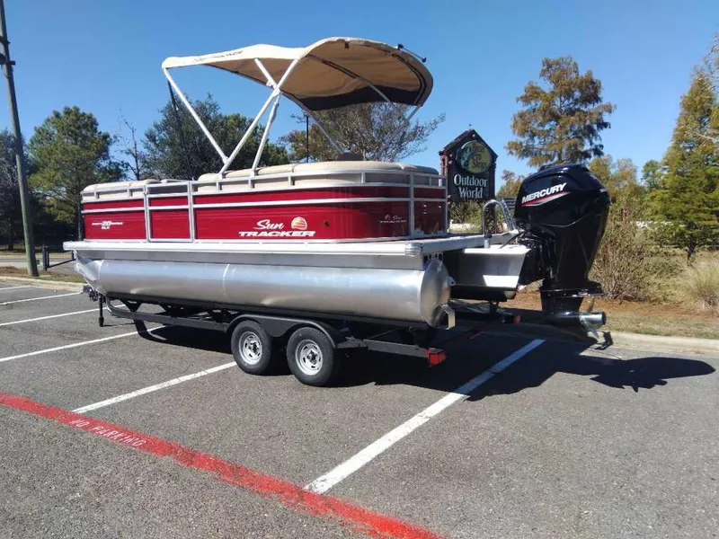 Slide: The Image of 2024 Sun Tracker Party Barge 20 DLX pontoon boat on trailer in parking lot. - 2