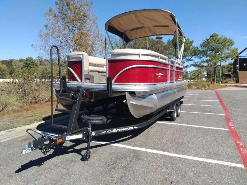 Slide: The Image of 2024 Sun Tracker Party Barge 20 DLX pontoon boat on trailer in parking lot. - 3