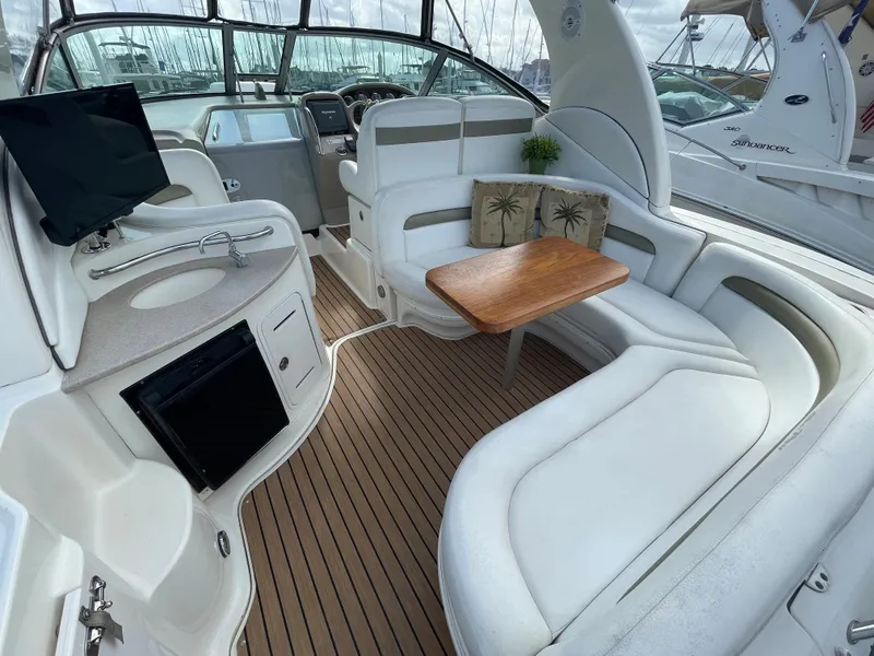 Slide: The Image of 2006 Sea Ray 320 Sundancer interior with white seating, wooden table, and modern amenities. - 12