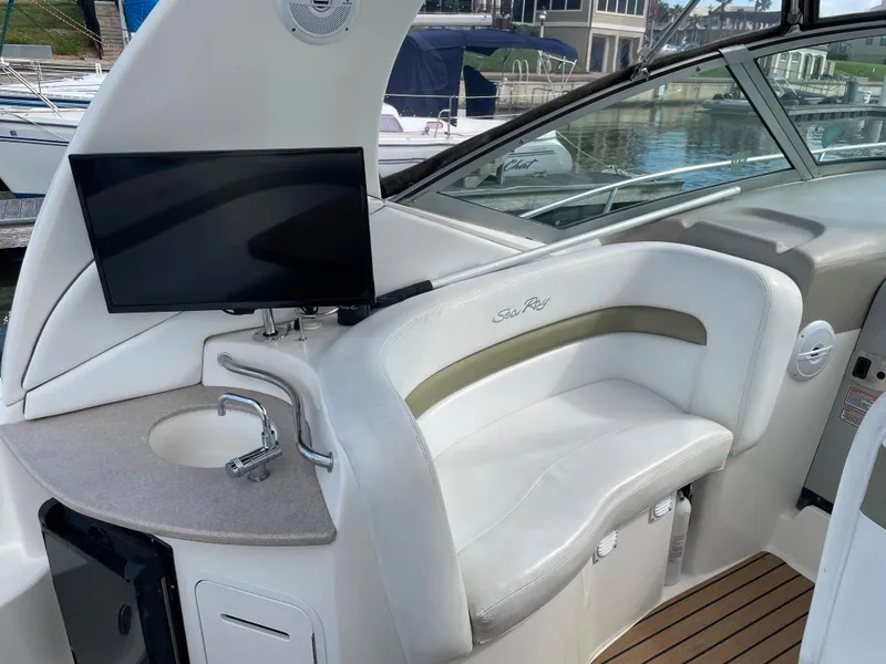Slide: The Image of 2006 Sea Ray 320 Sundancer cockpit with seating, sink, and mounted TV. - 18