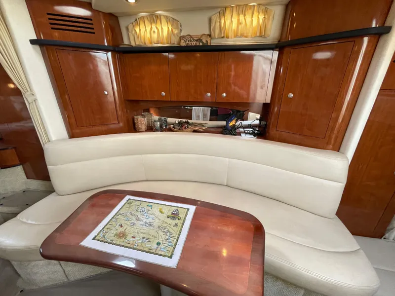Slide: The Image of Interior of 2006 Sea Ray 320 Sundancer with curved seating and wooden cabinetry. - 38