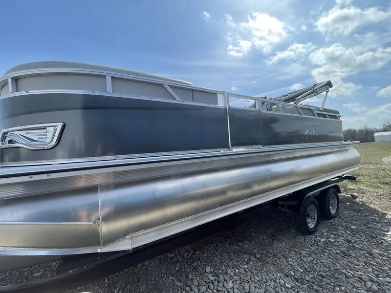 The Image of 2024 Avalon VENTURE 85 QL pontoon boat on a trailer under a blue sky. - 1