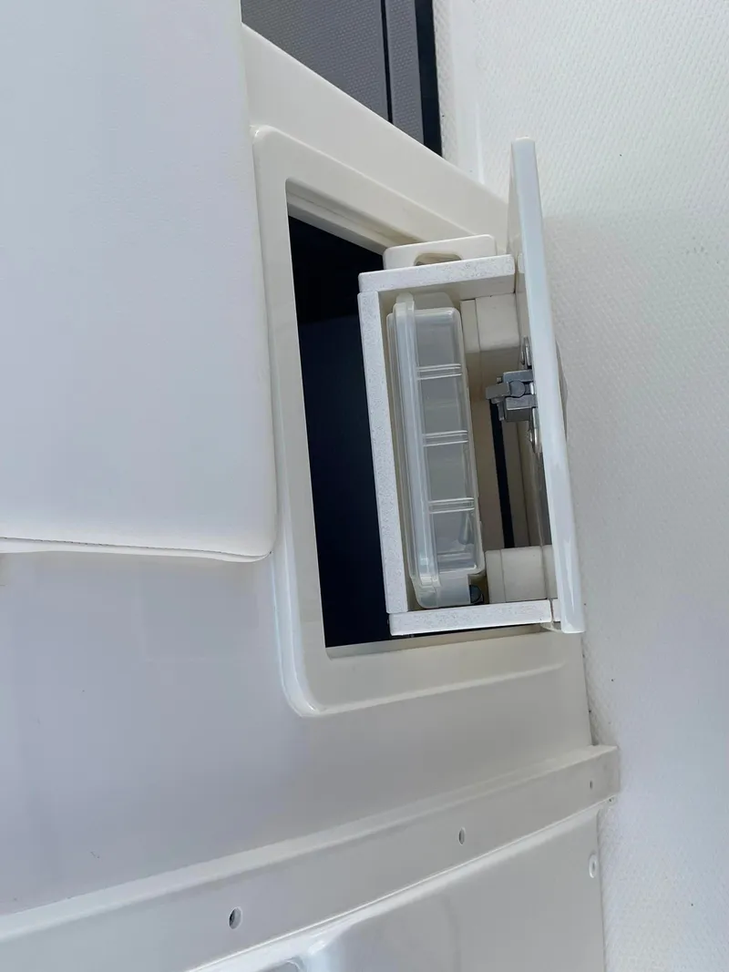 Slide: The Image of 2023 Robalo R270 storage compartment with clear container. - 27