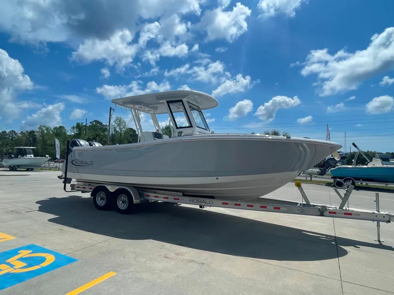 Slide: The Image of 2023 Robalo R270 boat on trailer under blue sky. - 2