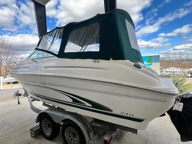 Slide: The Image of 1999 Sea Ray 215 Express Cruiser on a trailer with green canopy. - 2