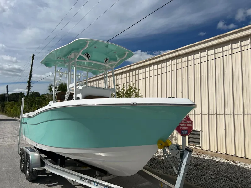 Slide: The Image of 2024 Clearwater 2200 boat on trailer, turquoise hull, white top, parked outdoors. - 24