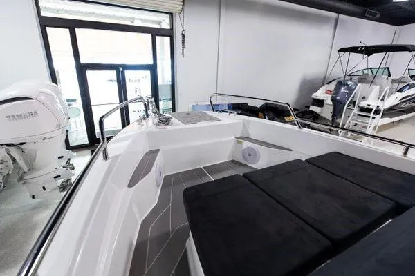 Slide: The Image of 2024 Quarken 27 Cabin boat interior with cushioned seating and Yamaha engine in showroom. - 15