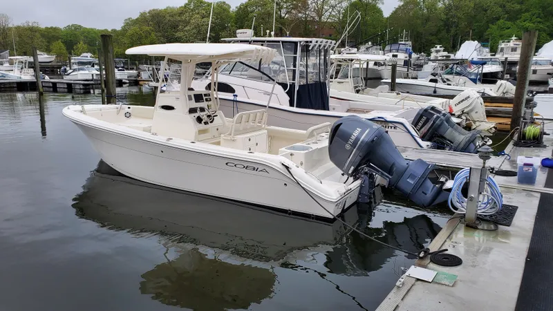 Slide: The Image of 2019 Cobia 240 CC boat docked at a marina. - 2