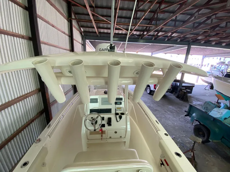 Slide: The Image of 2019 Cobia 240 CC boat interior with rod holders and steering console in a storage facility. - 5