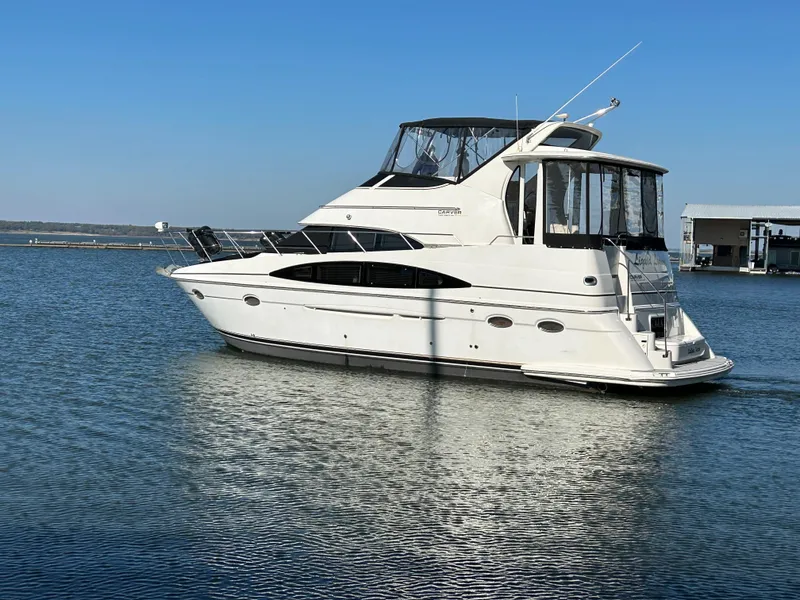 Slide: The Image of Luxury 2000 Carver 396 yacht cruising on calm waters under clear blue sky. - 40