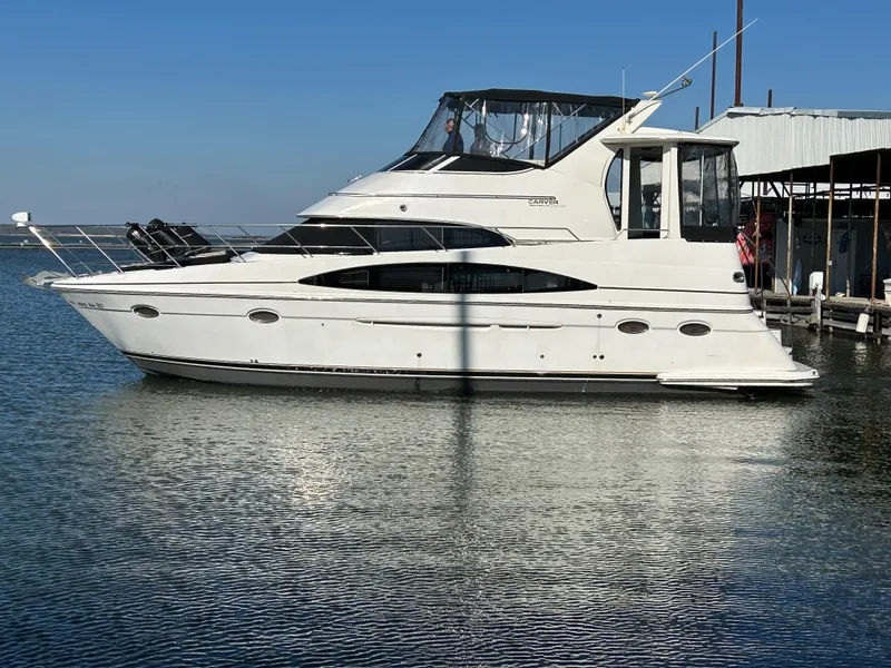 Slide: The Image of 2000 Carver 396 yacht docked on calm water under clear blue sky. - 41