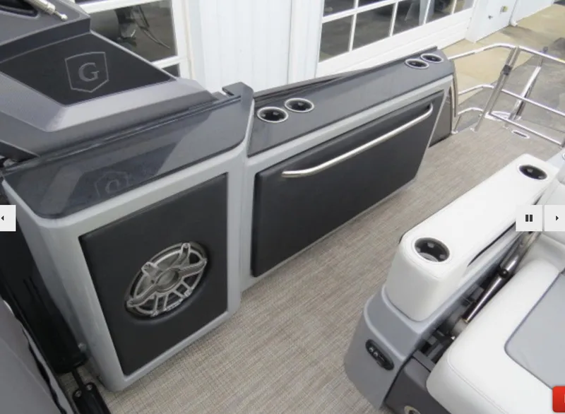 Slide: The Image of 2023 Godfrey AquaPatio 255 DFLW boat interior with cup holders and speaker. - 11