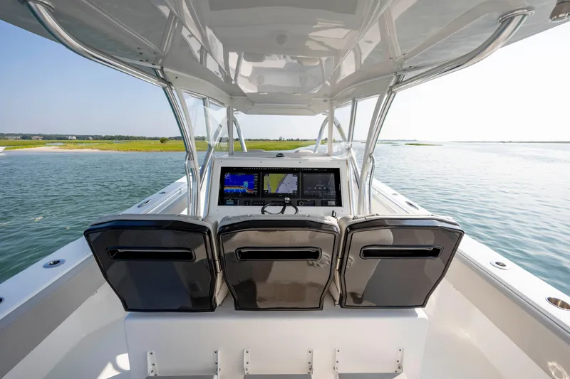 Slide: The Image of 2023 SeaHunter 46 CTS boat helm with triple seats and navigation screens on calm water. - 13