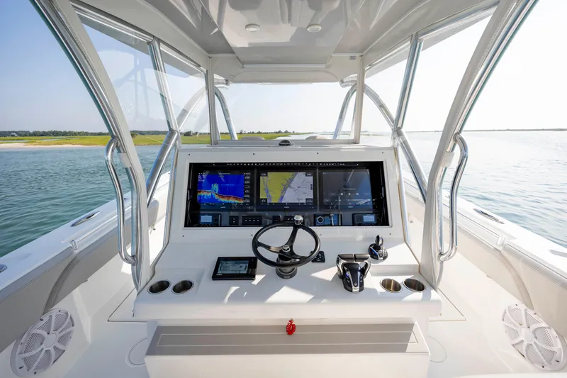 Slide: The Image of 2023 SeaHunter 46 CTS boat dashboard with advanced navigation screens and controls on open water. - 14