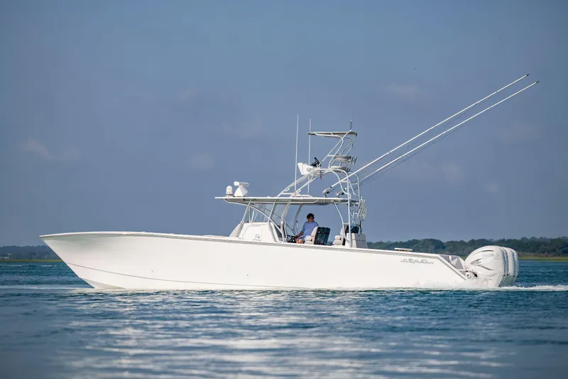 Slide: The Image of 2023 SeaHunter 46 CTS boat cruising on calm water under a clear blue sky. - 2