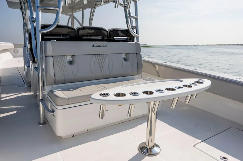 Slide: The Image of 2023 SeaHunter 46 CTS boat interior with seating and cup holders, on calm water. - 32