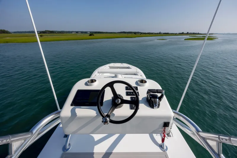 Slide: The Image of 2023 SeaHunter 46 CTS boat helm, steering wheel, and controls on calm water. - 35