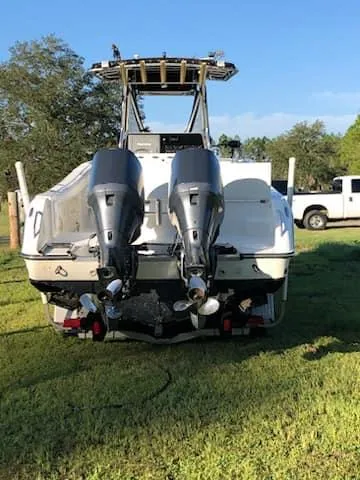 Slide: The Image of 2004 Triton 2690 CC boat with dual outboard motors on grassy area. - 9