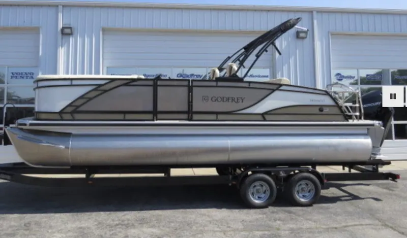 Slide: The Image of 2023 Godfrey Monaco 235 SFL pontoon boat on a trailer outside a dealership. - 1