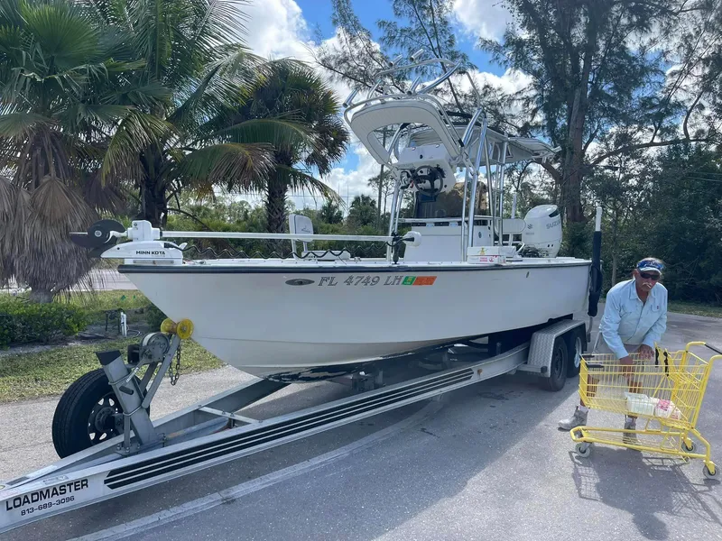 Slide: The Image of Man with shopping cart beside 2000 Avenger 24 boat on trailer. - 2