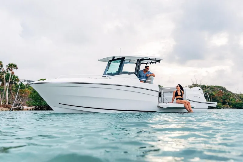The Image of 2027 Jeanneau Leader 9.0 CC boat on water with two people relaxing onboard. - 1