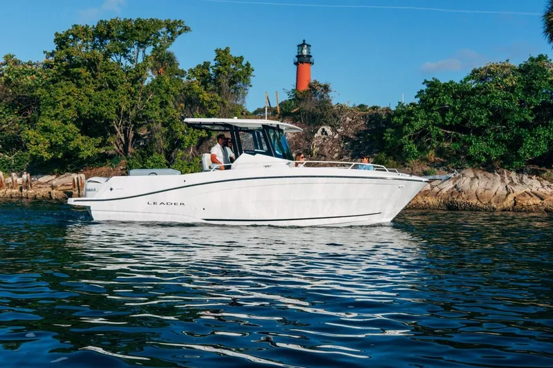Slide: The Image of 2027 Jeanneau Leader 9.0 CC boat cruising near a scenic lighthouse and lush greenery. - 16