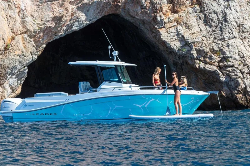 Slide: The Image of 2027 Jeanneau Leader 9.0 CC near rocky cave, with people paddleboarding. - 18