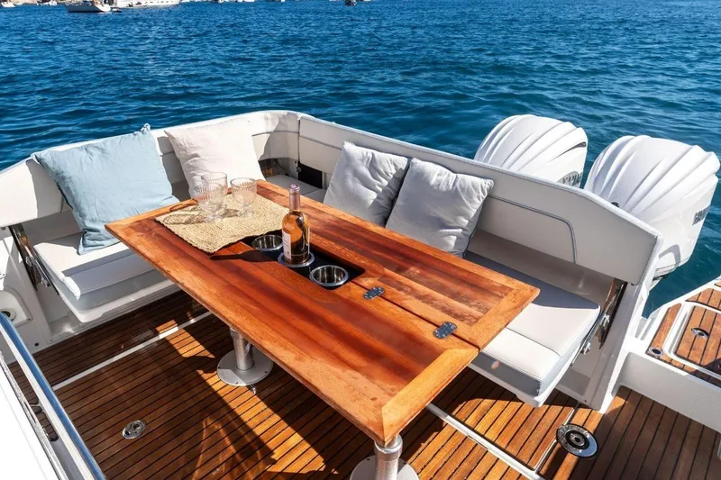 Slide: The Image of Luxurious Jeanneau Leader 9.0 CC boat interior with wooden table, cushions, and ocean view, 2027 model. - 5
