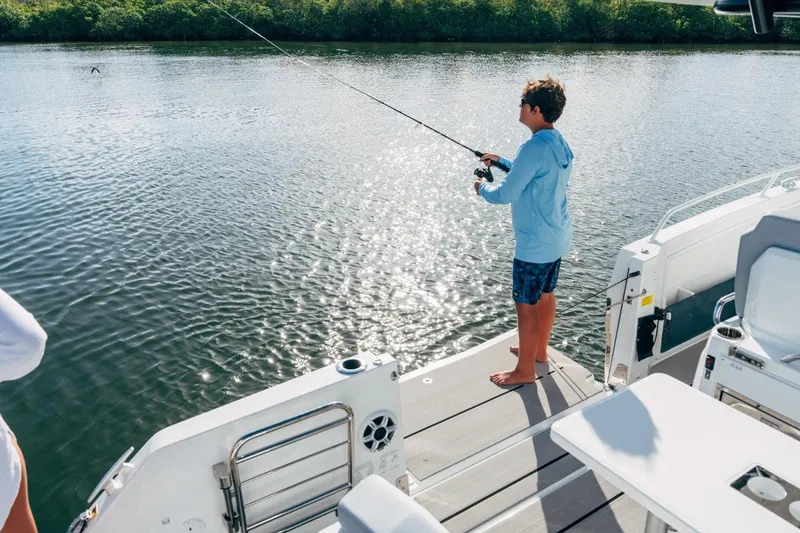 Slide: The Image of Boy fishing on a 2027 Jeanneau Leader 9.0 CC boat in sunny waters. - 9