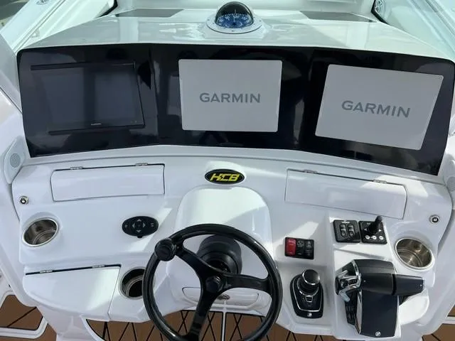 Slide: The Image of 2023 HCB 39 Speciale boat dashboard with Garmin navigation displays and steering wheel. - 7