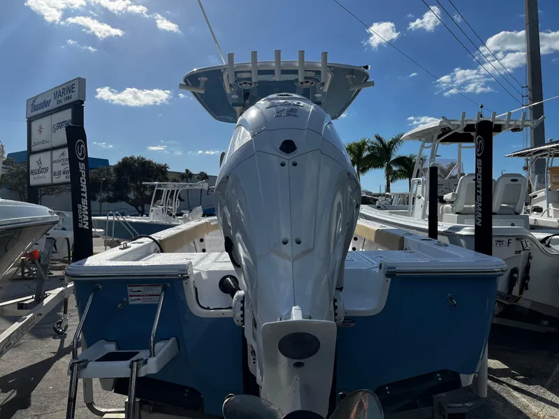 Slide: The Image of 2024 Sportsman Masters 247OE Bay Boat with outboard motor, docked under clear sky. - 2