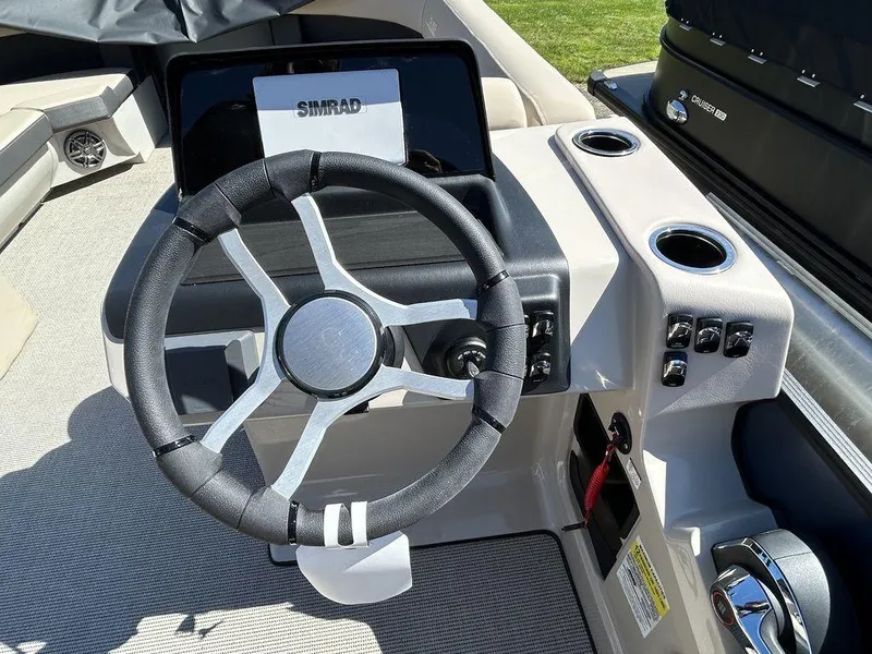 Slide: The Image of 2024 Harris Cruiser 230 boat dashboard with steering wheel and Simrad display. - 13