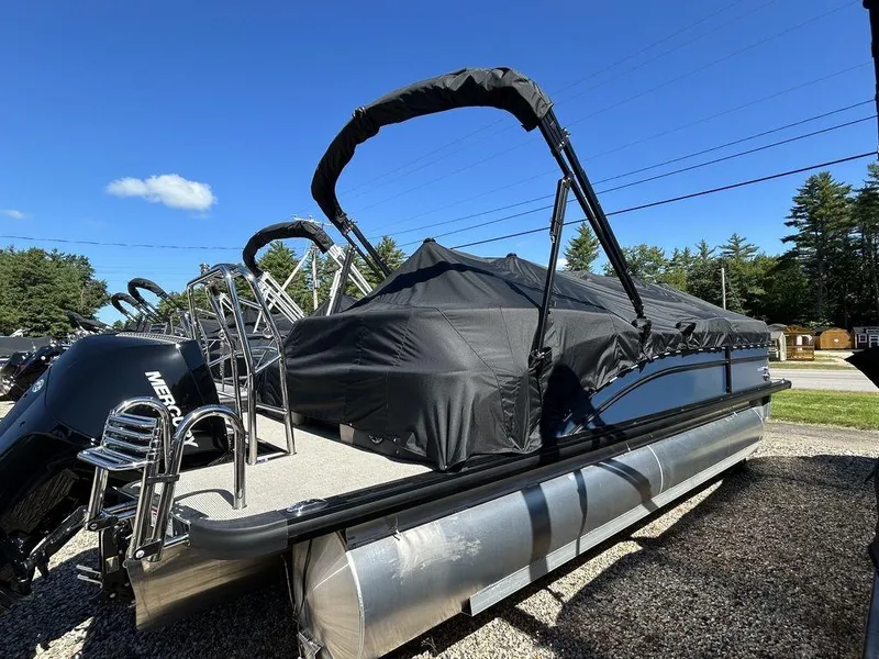 Slide: The Image of 2024 Harris Cruiser 230 pontoon boat with cover, parked outdoors under clear blue sky. - 5