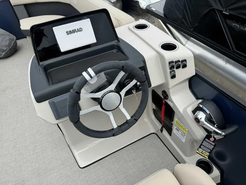 Slide: The Image of 2024 Harris Cruiser 230 helm with steering wheel, Simrad display, and control panel. - 6