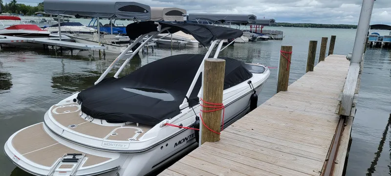 Slide: The Image of 2023 Monterey 224FS boat docked at a marina with a black cover. - 3