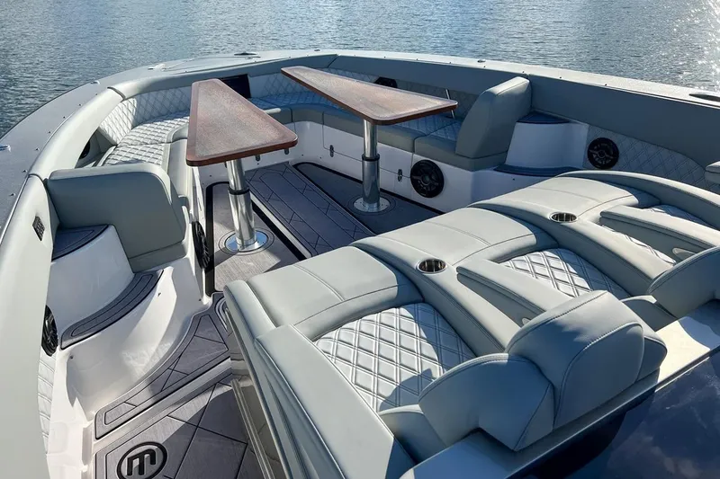 Slide: The Image of Luxurious 2024 Mystic Powerboats M5200 interior with elegant seating and wooden tables. - 4