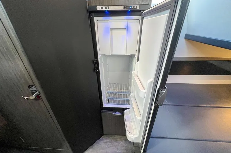 Slide: The Image of 2024 Mystic Powerboats M5200 interior with open refrigerator and modern design. - 6