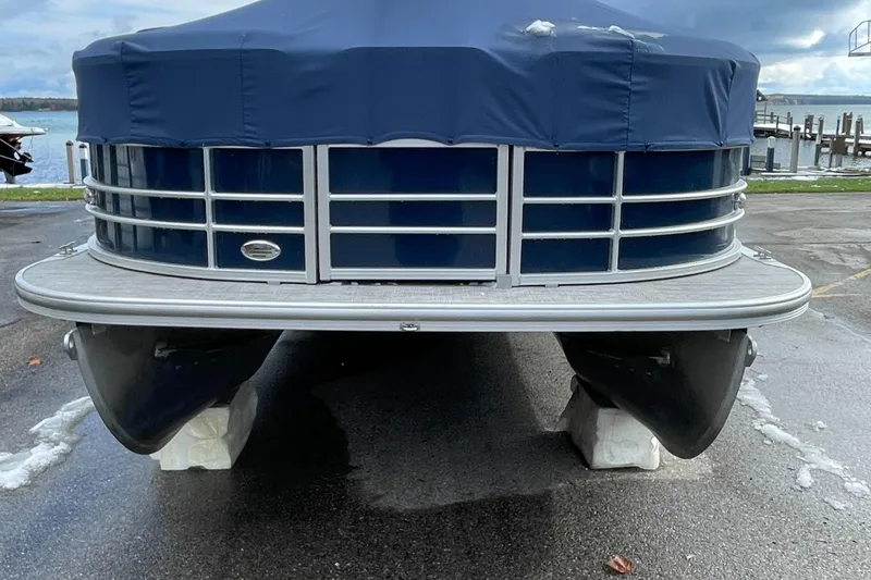 Slide: The Image of 2022 Berkshire 24RFXLE25 pontoon boat with blue cover, docked on a concrete surface. - 2