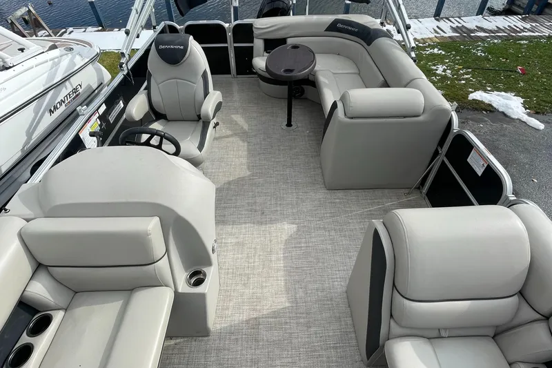 Slide: The Image of 2022 Berkshire 22CL2LE25 pontoon boat interior with plush seating and a central table. - 3