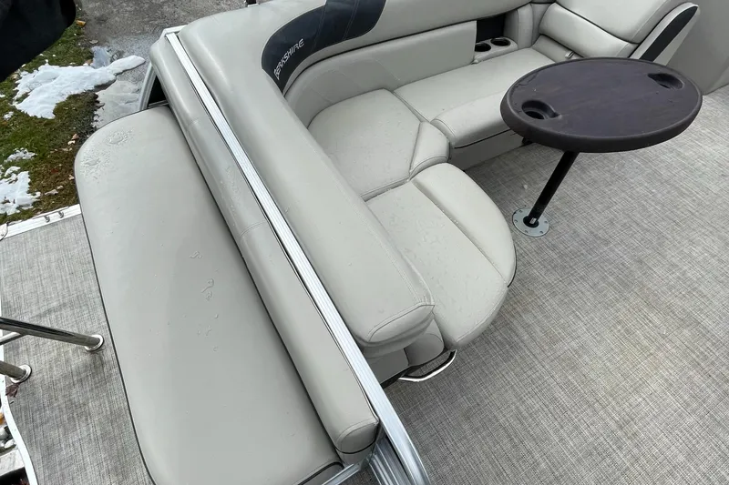 Slide: The Image of 2022 Berkshire 22CL2LE25 pontoon boat interior with beige seating and a round table. - 4