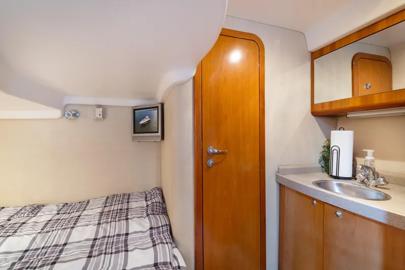 Slide: The Image of Cozy cabin interior of 2004 Regal 4260 Commodore with bed, sink, and wooden door. - 19