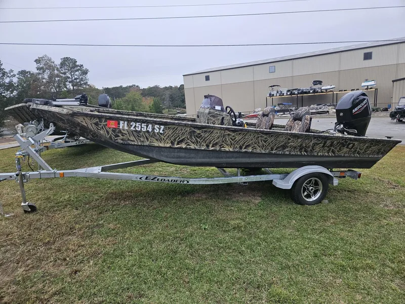 Slide: The Image of 2021 Lund 1760 Predator SC boat on EZ Loader trailer, camo design, parked outdoors. - 10