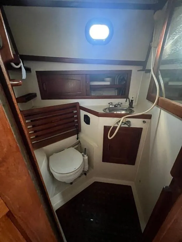 Slide: The Image of 1986 Pacific Seacraft 37 sailboat bathroom with wooden cabinetry and porthole window. - 11