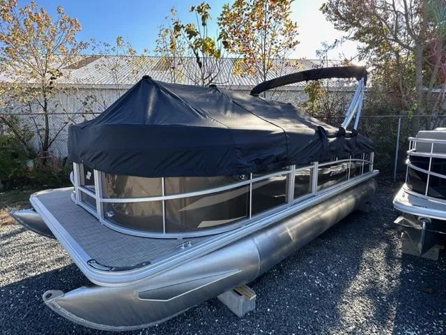 Slide: The Image of 2024 Starcraft LX 20 CB pontoon boat with black cover, parked outdoors. - 7