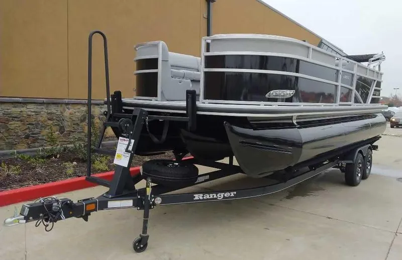 Slide: The Image of 2024 Ranger Reata 223C pontoon boat on a trailer in a parking lot. - 1