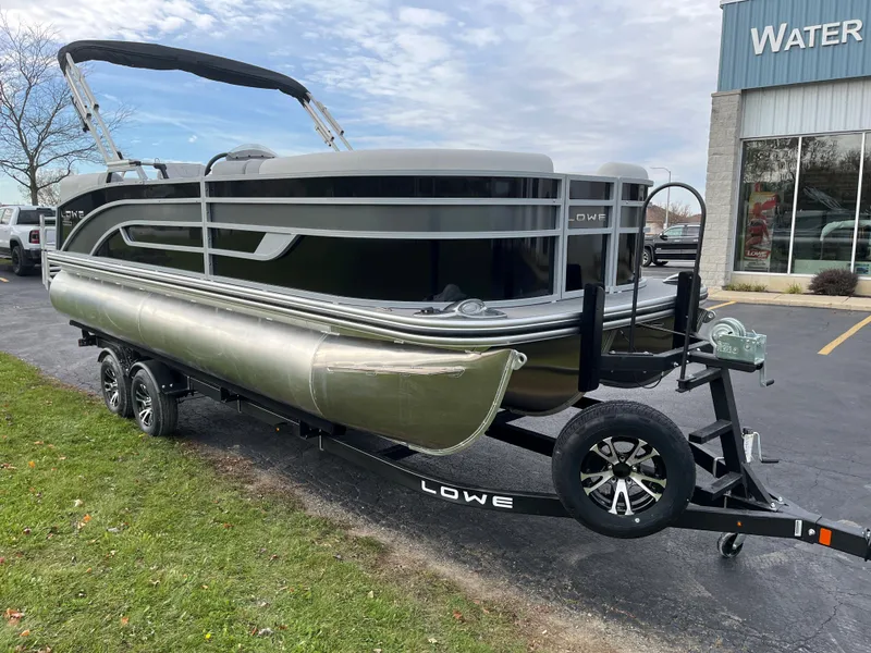 Slide: The Image of 2024 Lowe SS 210 WT pontoon boat on trailer outside dealership. - 2
