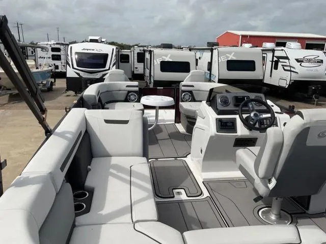 Slide: The Image of 2023 Hurricane FD2260F boat interior with seating, steering console, and RVs in the background. - 3